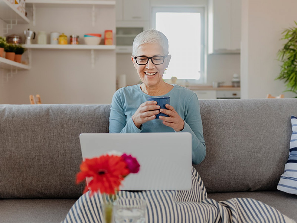 Woman sitting on couch looking at laptop