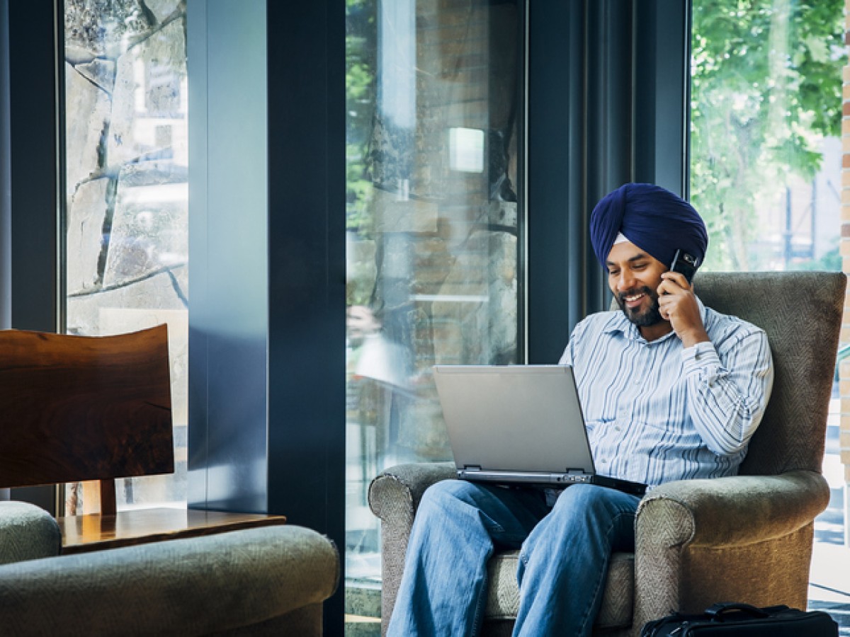 South Asian man with cell phone and laptop