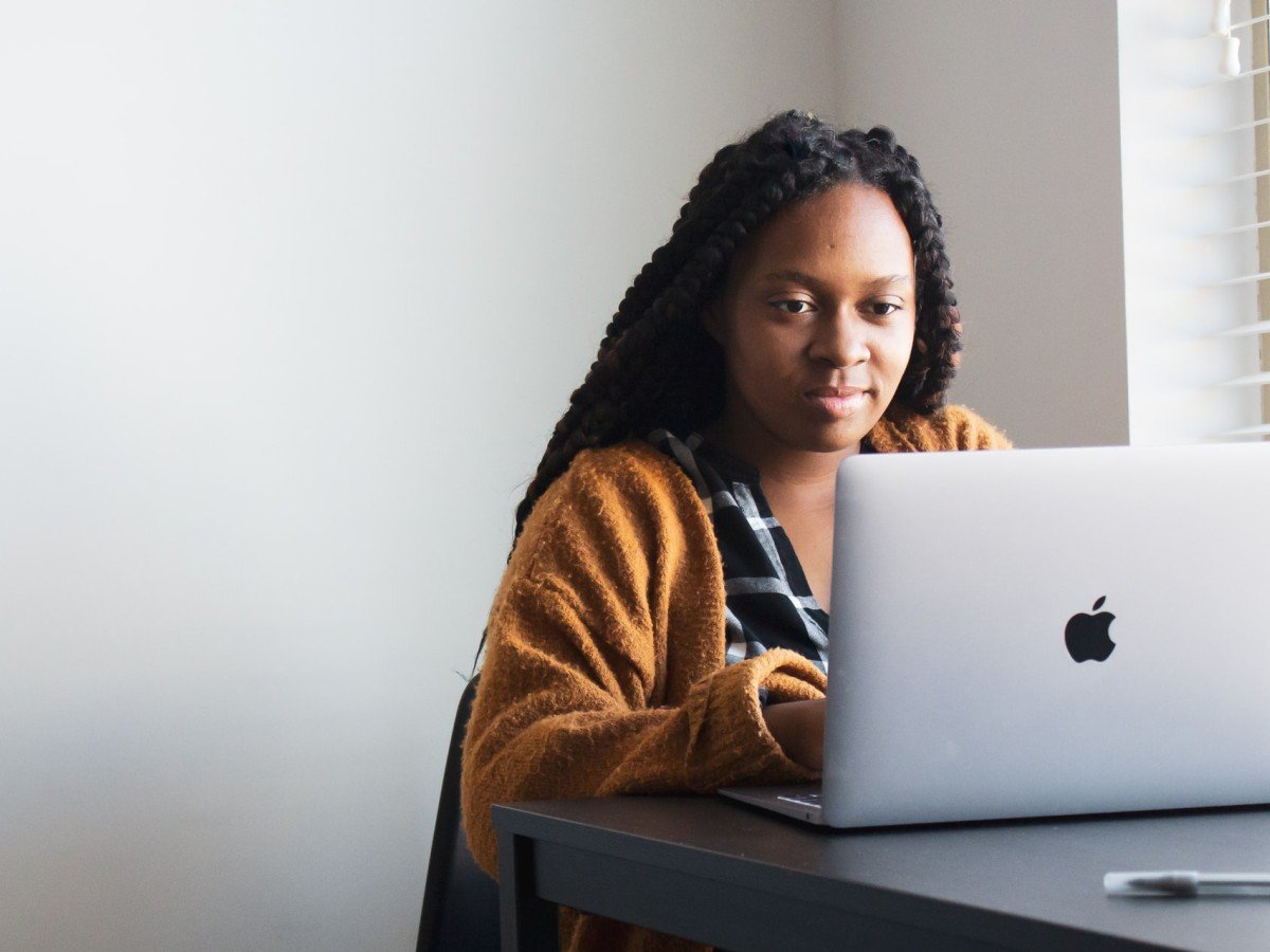 Black woman at desk in front of Mac laptop