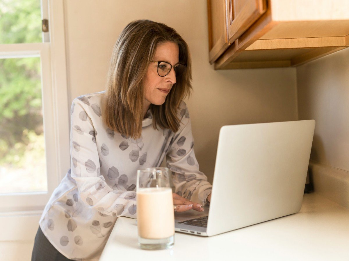 Middle-aged woman using laptop in kitchen