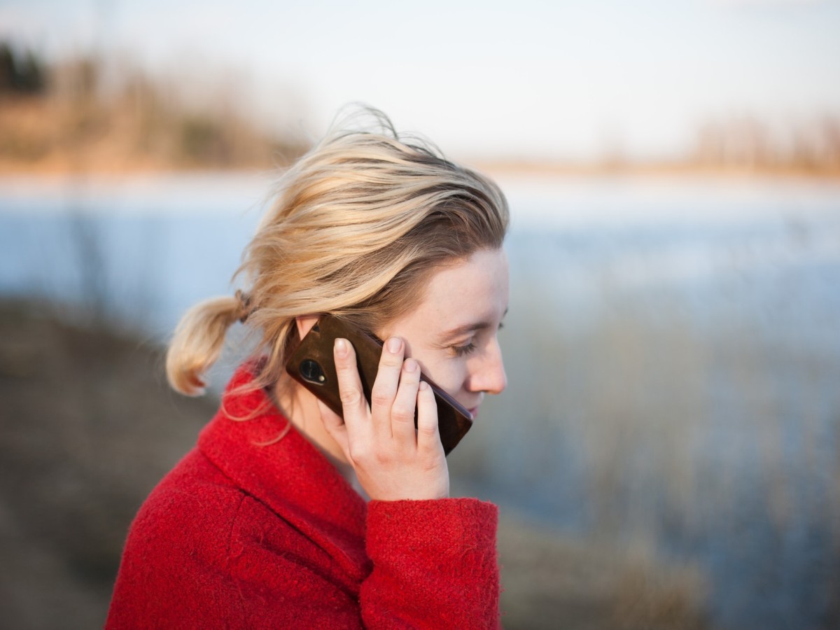 Woman on phone outdoors, by a lake