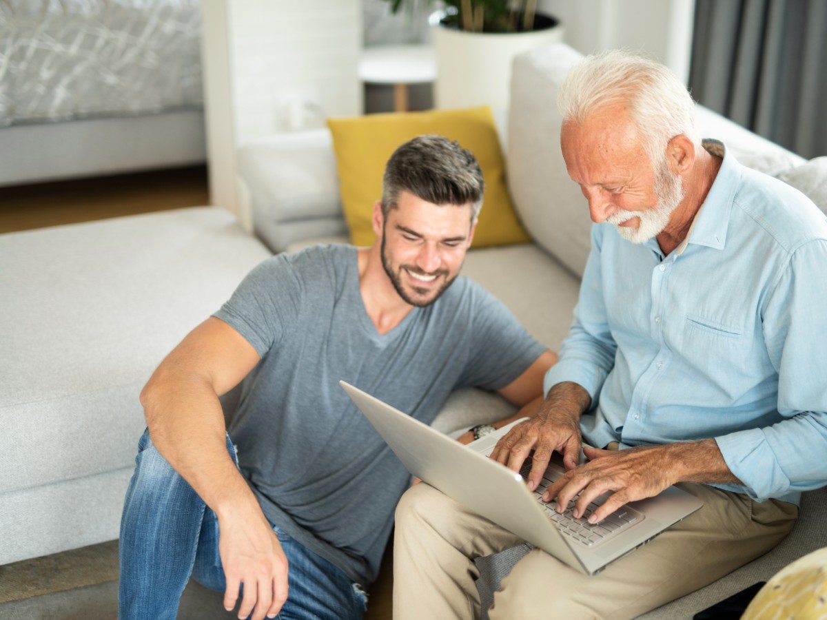 Two men, one senior, watching webinar on laptop