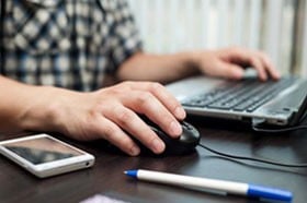 male typing at a laptop