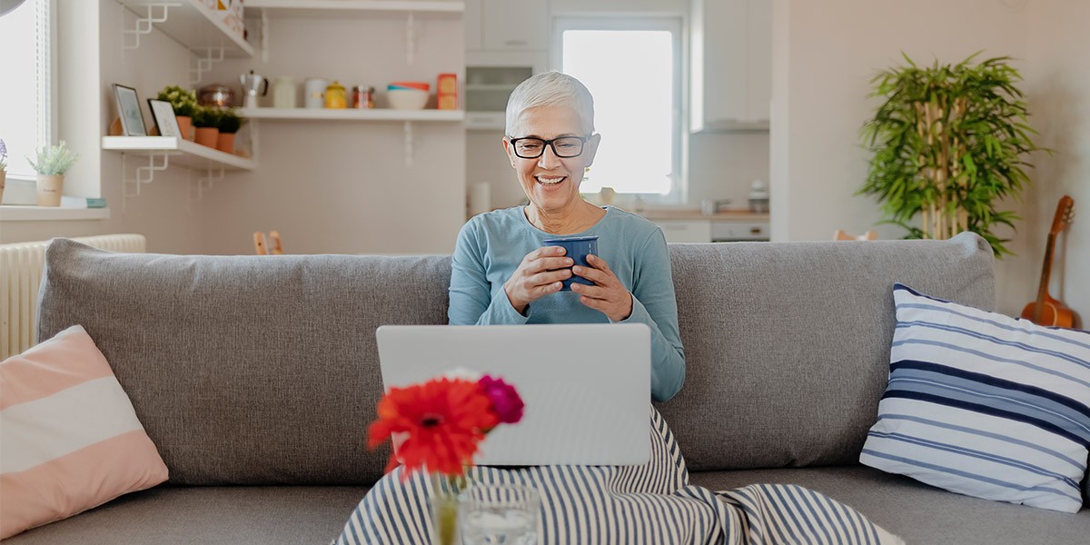 Woman sitting on couch looking at laptop