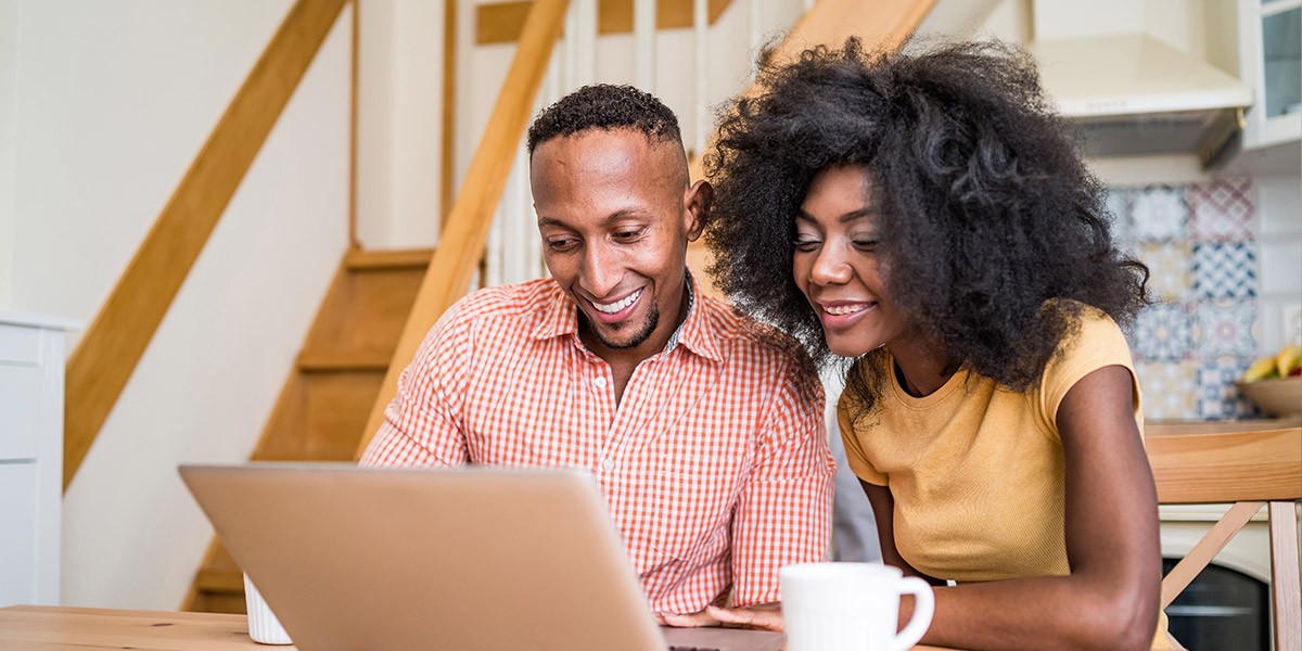 Young couple in kitchen looking at a laptop together
