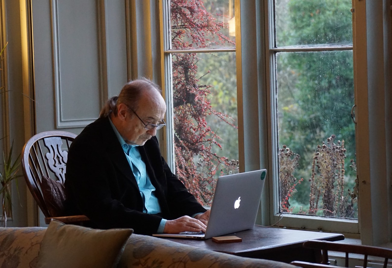 Older man with laptop beside a window