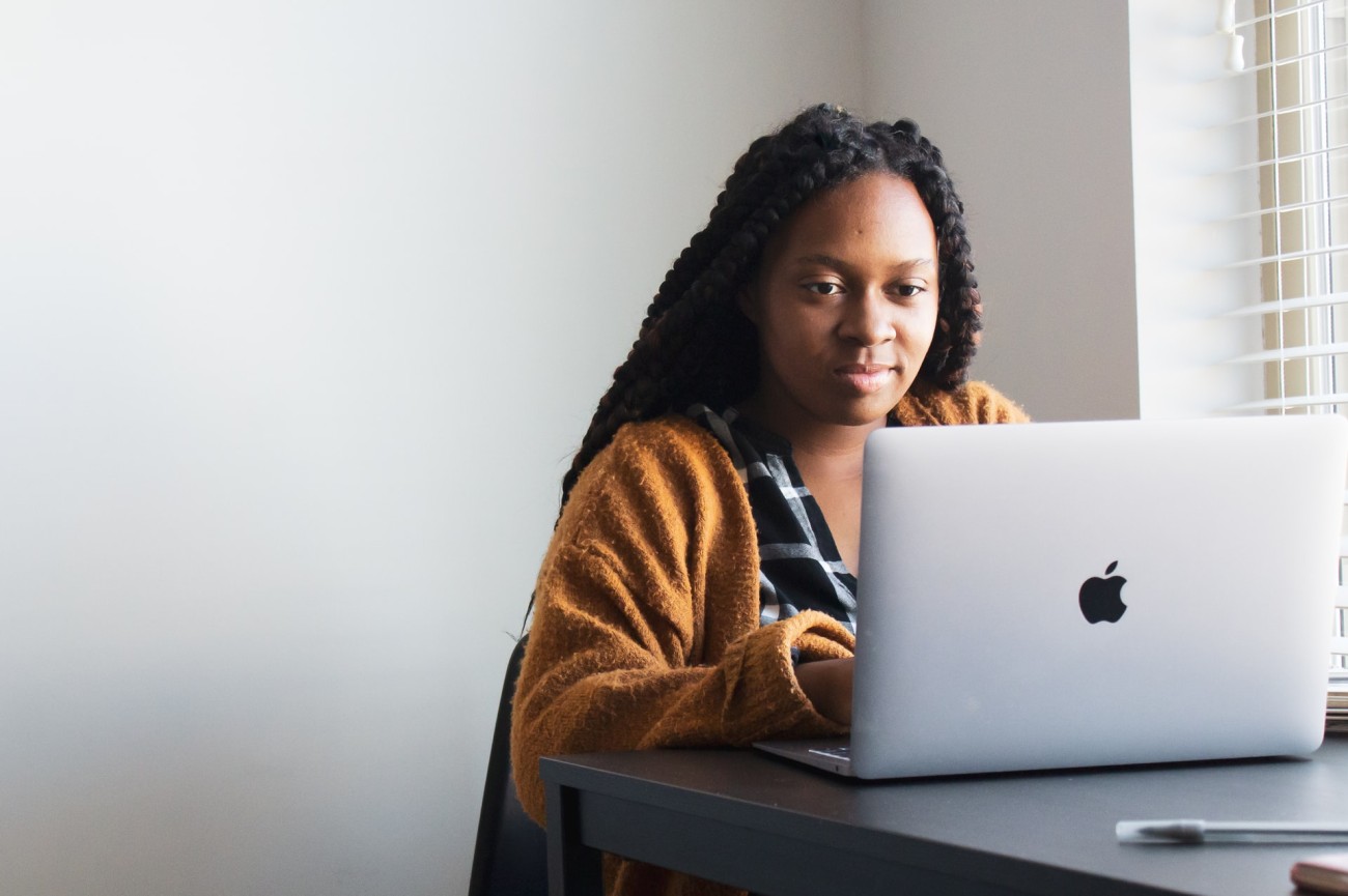Black woman at desk in front of Mac laptop