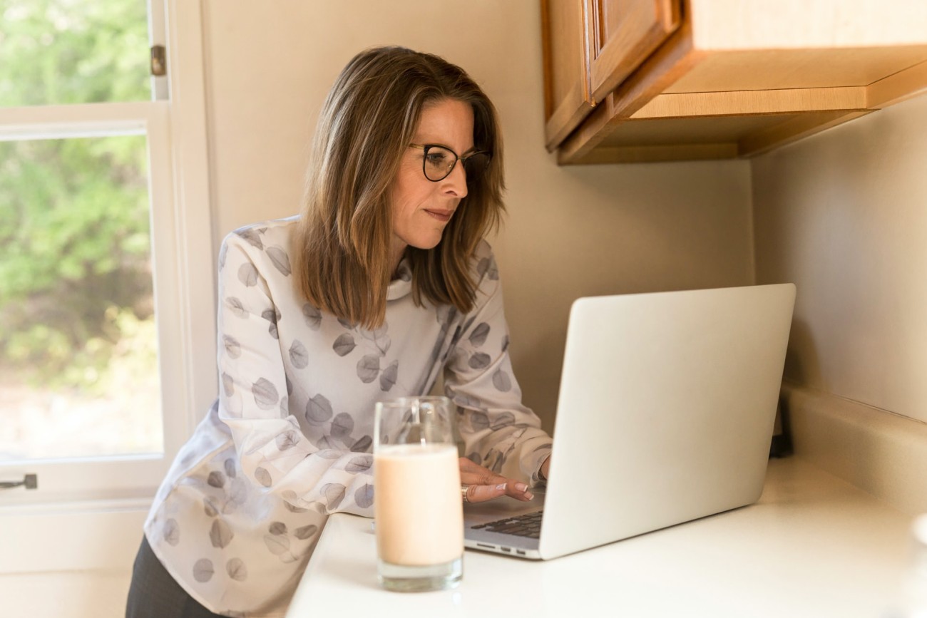 Middle-aged woman using laptop in kitchen