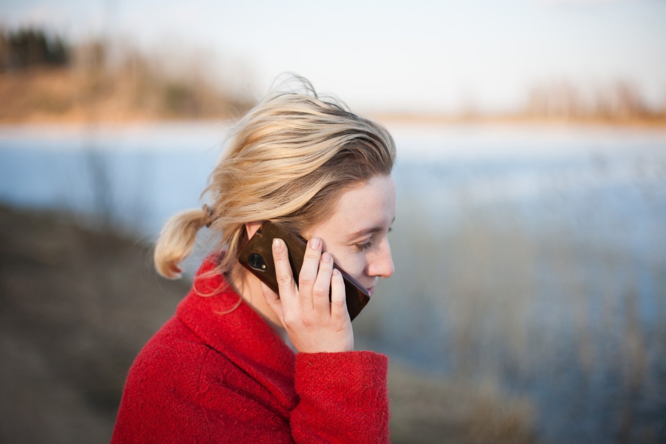 Woman on phone outdoors, by a lake