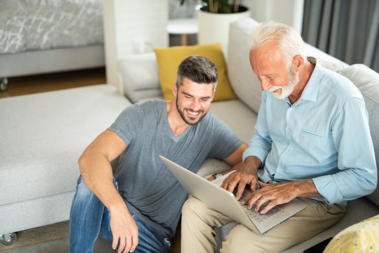 Two men, one senior, watching webinar on laptop