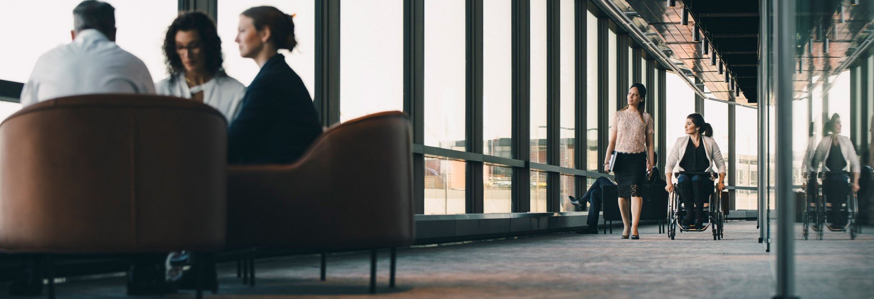 Hallway of building with people sitting in chairs or walking