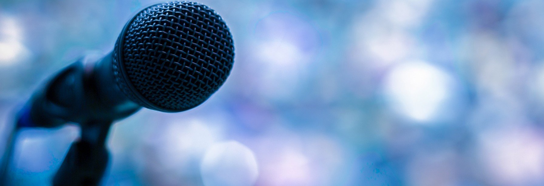 Microphone silhouette in front of a blurry crowd