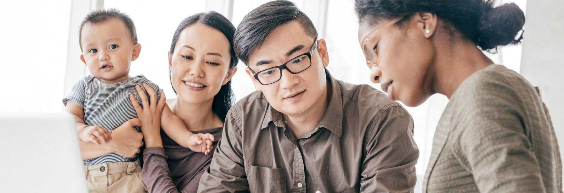 Man and woman with their child going through financial documents with their advisor