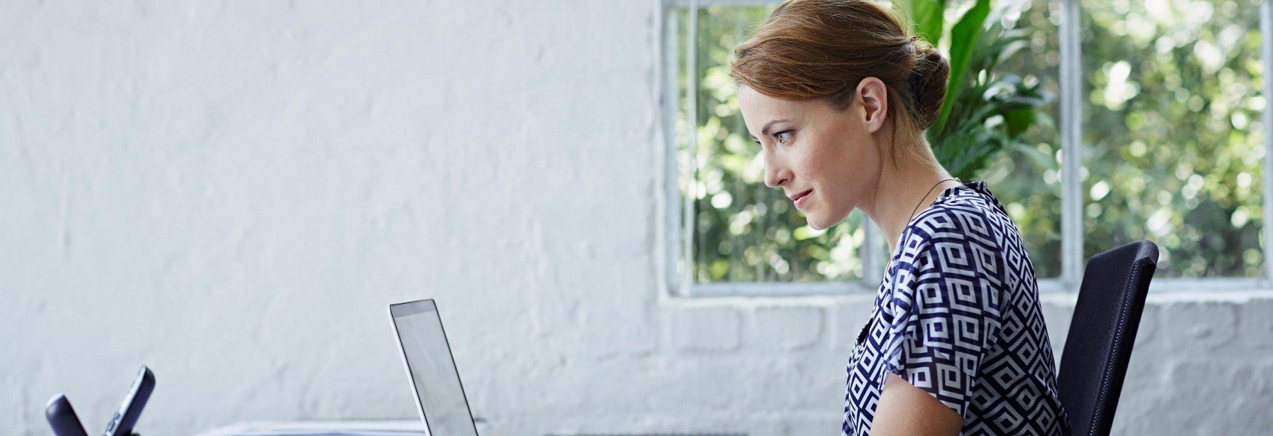 Woman sitting at desk in front of laptop