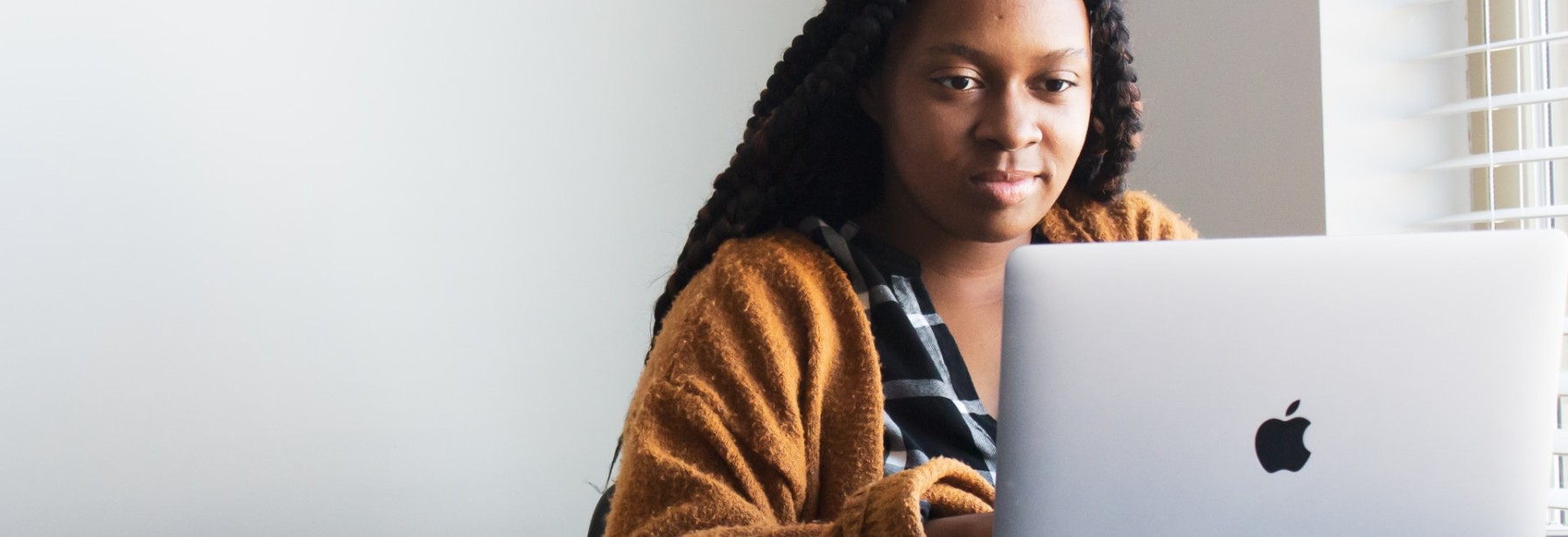 Black woman at desk in front of Mac laptop