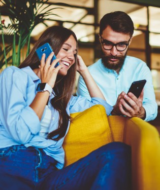 Couple sitting on couch each on their own phones