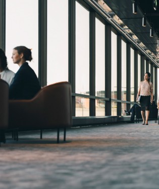 Hallway of building with people sitting in chairs or walking