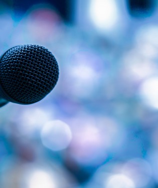 Microphone silhouette in front of a blurry crowd