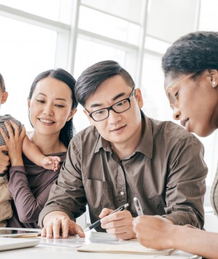 Man and woman with their child going through financial documents with their advisor